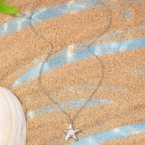 Détail macro du collier pendentif étoile de mer avec texture en spirale sur fond de sable