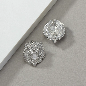 Macro detail of silver lion head stud earrings with intricate embossed textures