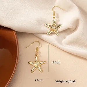 Détail des boucles d'oreilles étoile de mer bohème avec texture martelée dorée sur velours