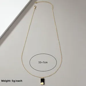 Detail of gold chain necklace with black checkered rectangular pendant and size markings