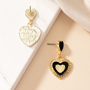 Macro detail of gold vintage heart earrings featuring black enamel and radial textures