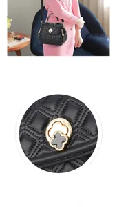 Detail of a black quilted shell shoulder bag with a gold clover clasp and top handle