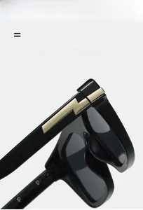 Détail de lunettes de soleil noires avec charnière éclair dorée et branche flexible