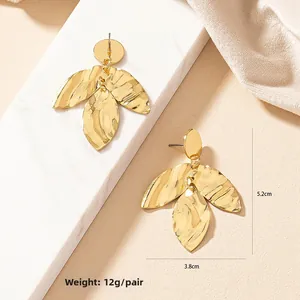 Detailed view of gold leaf earrings with irregular hammered texture and triple-layer design