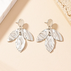 Macro shot of silver leaf earrings featuring irregular hammered textures and layered metal design