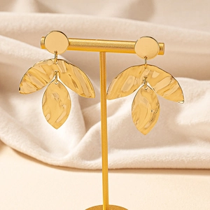 Golden irregular textured leaf earrings with hammered finish on a jewelry display stand