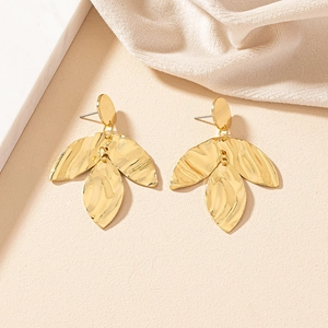 Macro detail of golden irregular texture leaf earrings with hammer pattern craftsmanship