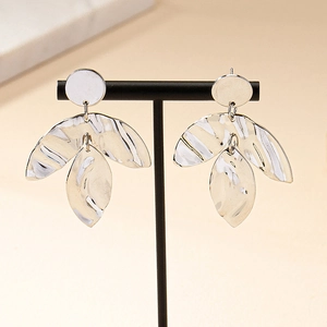 Macro shot of silver-tone leaf earrings with hammered texture on black display stand