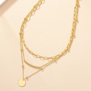 Close-up of golden multi-layer necklace with paperclip chain and round disc pendant