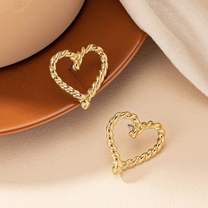 Boucles d'oreilles cœur torsadées dorées posées sur une assiette en céramique vintage