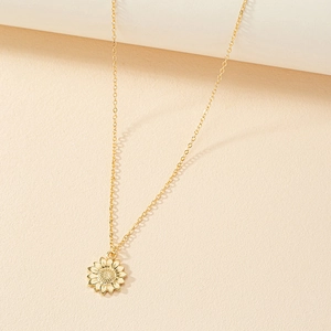 Elegante collana con pendente a girasole dorato e petali dettagliati su sfondo beige