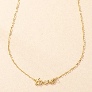 Close-up of golden LOVE pendant necklace with minimalist cursive font and fine cross chain
