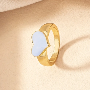 Makroaufnahme von Herzring in Gold mit weißer Emaillierung auf minimalistischem Hintergrund