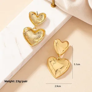 Macro detail of gold heart earrings showing polished finish and dimensions 5.1cm by 2.9cm