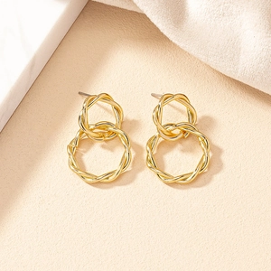 Detailed close-up of golden dual interlocking twisted hoops on elegant textured background