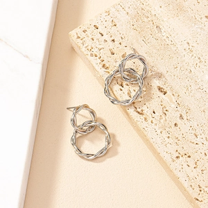 Silver twisted geometric circle earrings in a double hoop design on natural stone surface