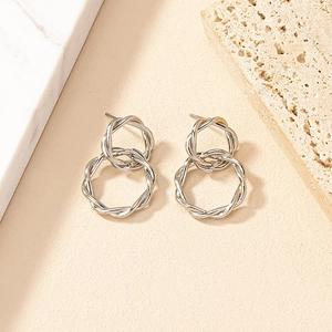 Macro detail of silver twisted rope double ring earrings with polished metal texture