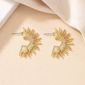 Golden sunburst fan earrings with a textured radiant design on a neutral background