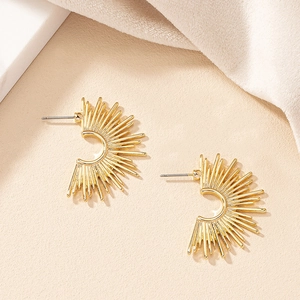 Macro shot of gold sunburst stud earrings with textured semi-circle metal rays