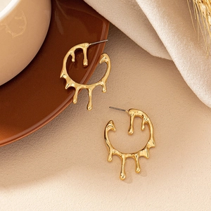 Elegant gold lava drop earrings in irregular circular design on a minimalist textured setup
