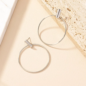 Close-up of silver geometric hoop earrings featuring a minimalist metal bar design