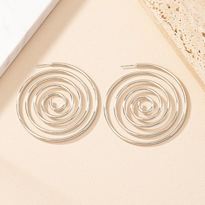 Macro detail of silver spiral hoop earrings on beige background with stone props