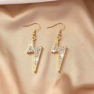 Élégantes boucles d'oreilles éclair dorées avec cristaux pavés sur fond de soie de luxe