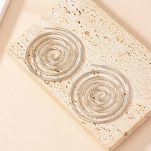 Minimalist silver spiral hoop earrings shown from a 45-degree angle on a beige stone base
