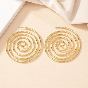 Close-up of golden oversized spiral hoop earrings on an elegant minimalist background