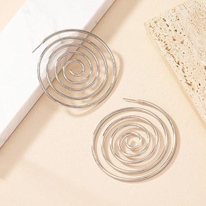 Macro shot of silver spiral hoop earrings with minimalist geometric design on stone