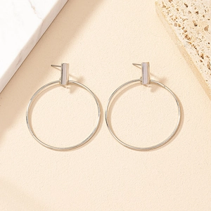 Detailed view of silver geometric hoop earrings on textured marble and stone background