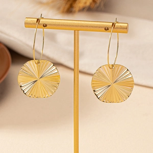 Golden sunburst texture round earrings on minimalist display stand with warm background