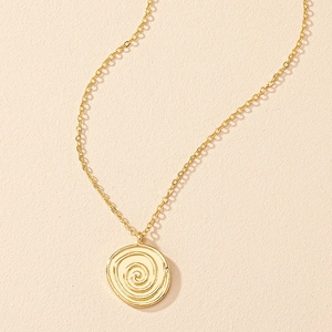 Detail of a golden pendant necklace with a spiral texture on a beige background