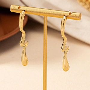 Elegant gold irregular wave drop earrings with a polished liquid metal texture on stand