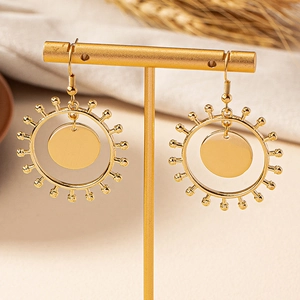 Boucles d'oreilles soleil dorées avec disques polis présentées sur un support en T