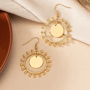 Boucles d'oreilles pendantes soleil dorées bohèmes avec perles sur tissu chaleureux