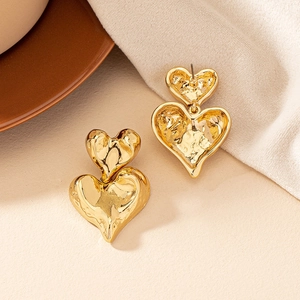 Detailed view of gold double heart earrings with irregular lava textured metal surface