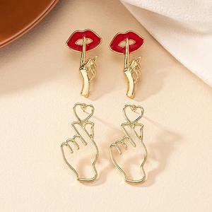 Detailed shot of trendy red lip and finger heart gesture earrings on beige leather texture