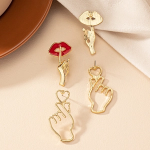 Macro detail of gold red lip and heart-shaped metal earrings on sand background