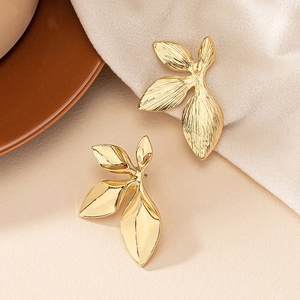 Close-up of golden petal earrings with brushed metallic texture and artistic leaf design