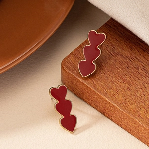 Detail showing the red enamel triple heart drop earrings with gold metallic edges