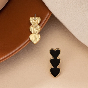 Close-up of triple heart earrings with black enamel finish and gold-plated metal base