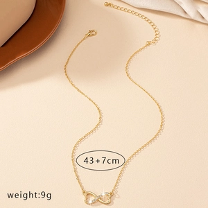 Collier doré double cœur et symbole infini avec cristaux sur fond texturé beige clair