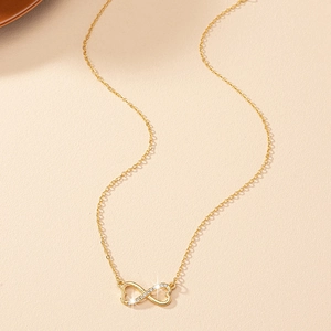 Détail du collier coeur infini doré avec zircons étincelants sur un fond chaleureux