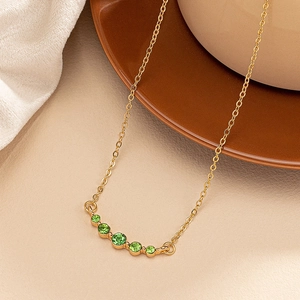 Detail of vintage gold necklace featuring five graduated green emerald zirconia stones