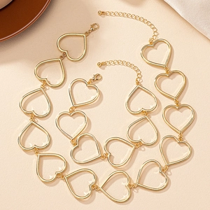 Detalle de collar con eslabones de corazón dorados con cierre de langosta y sombras suaves