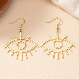 Detail of golden geometric evil eye hook earrings on a textured minimalist background
