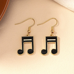 Close-up of gold and black musical note drop earrings with detailed enamel finish
