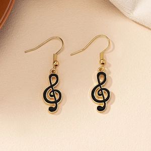 Close-up of golden treble clef earrings with black enamel inlay and hooks