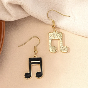 Detail of music note earrings in gold brushed texture and black enamel finish